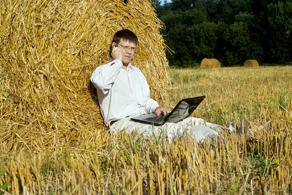 Бизнесмен с ноутбуком рядом с стогами сена — стоковое фото