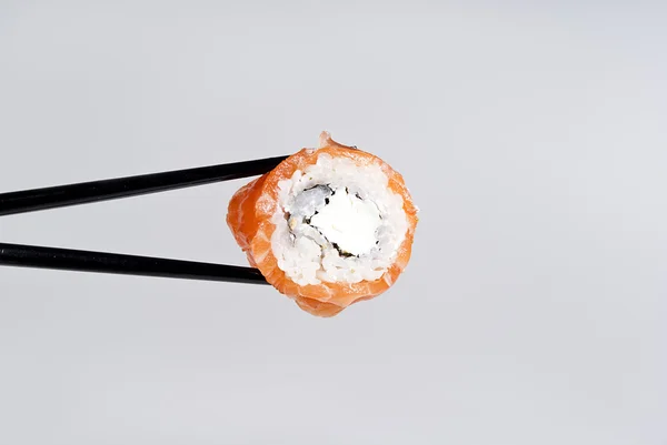Delicioso sushi en un palo sobre un fondo de gris — Foto de Stock