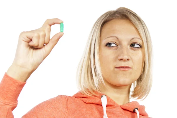 Girl looks at the pill and doubts — Stock Photo, Image