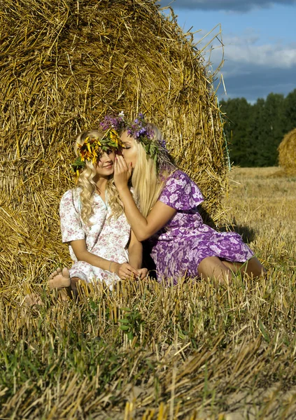 Flicka sitter nära en höstack i fältet — Stockfoto