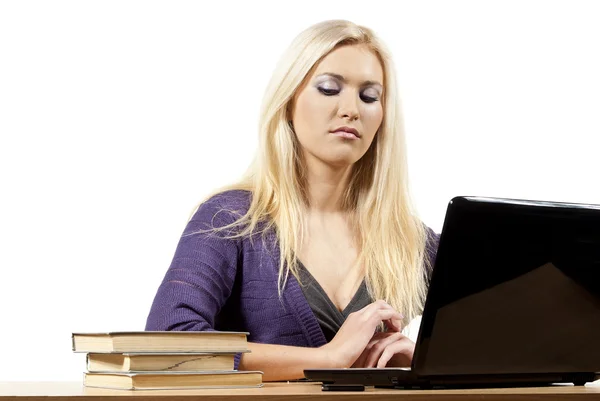 Meisje met laptop kijken naar boeken — Stockfoto