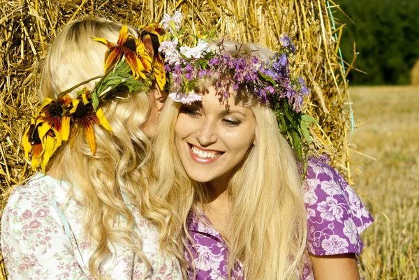 Dívky poblíž stohy sena s věnci na hlavách — Stock fotografie
