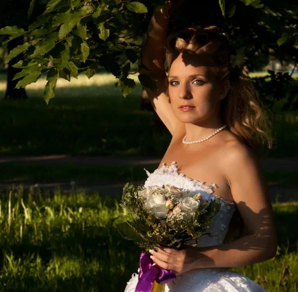 Hermosa chica en un vestido de novia con ramo — Foto de Stock