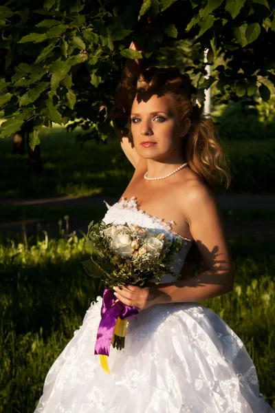 Красивая девушка в свадебном платье с букетом — стоковое фото