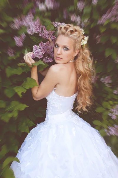 Beautiful girl in a wedding dress with lilac — Stock Photo, Image