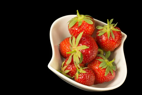 Frische Erdbeeren in weißer Schüssel auf schwarzem Hintergrund. — Stockfoto