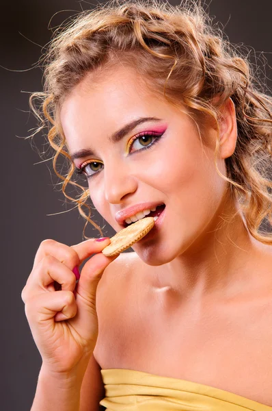 Portrét mladé ženy jíst cookie — Stock fotografie