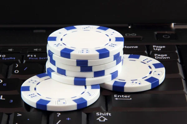 Stack of white casino gambling chips on keyboard