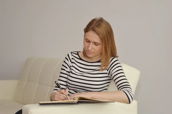 Молодая женщина пишет в календаре Лицензионные Стоковые Изображения