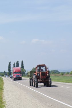 Queue on the road with tractor and other cars clipart