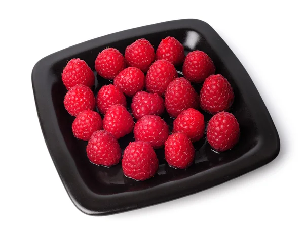 Raspberry pada piring hitam terisolasi pada latar belakang putih — Stok Foto
