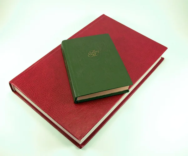 A little green book on a big red book