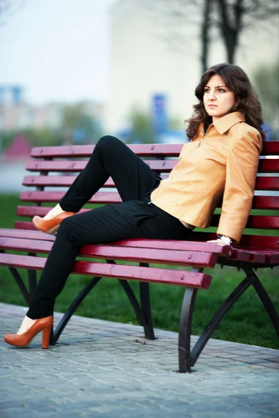 Chica en un parque de la ciudad en un banco — Foto de Stock