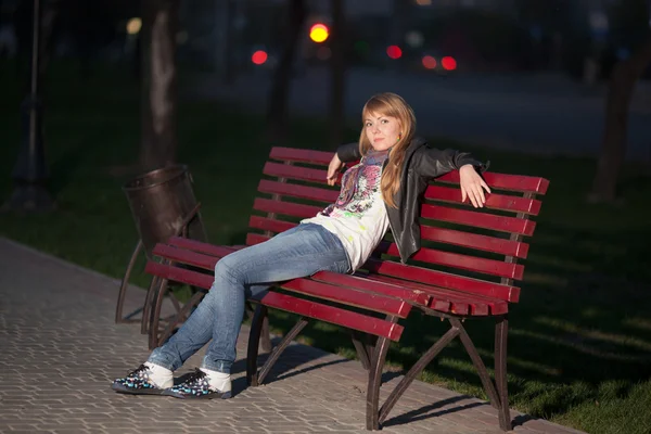 Menina em um parque da cidade em um banco — Fotografia de Stock
