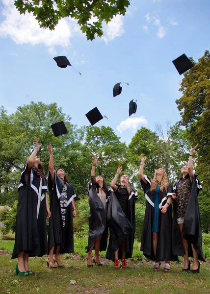 Выпускники бросают в небо академические шапки — стоковое фото
