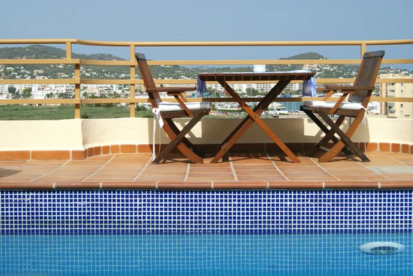 Table et chaises près de la piscine dans le jardin sur le toit dans la ville méditerranéenne — Photo