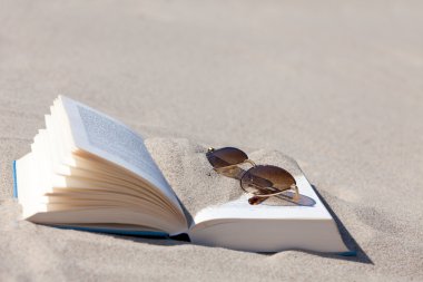 plaj açık bir kitap üzerinde yatıyor kahverengi renkli lensler ile güneş gözlüğü