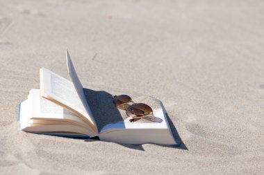 plaj açık bir kitap üzerinde yatıyor kahverengi renkli lensler ile güneş gözlüğü