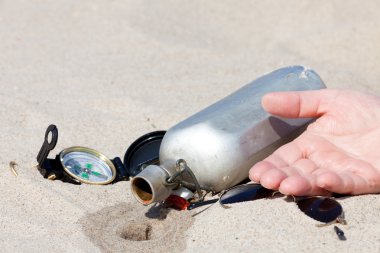 Human hand lies next to an empty canteen in the desert clipart