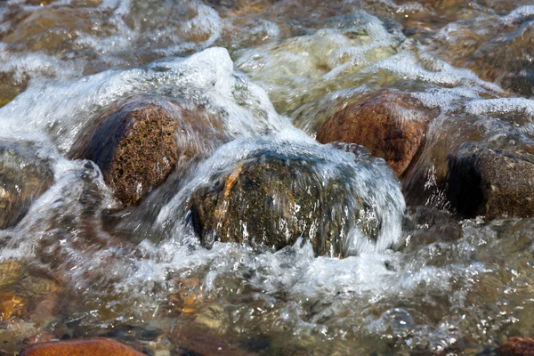 stock image Crystal-clear water bubbles over rocks on the coast