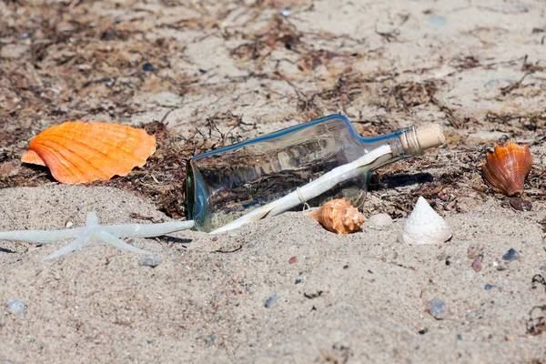 Flaschenpost am Strand mit Muscheln und Seesternen — Stockfoto