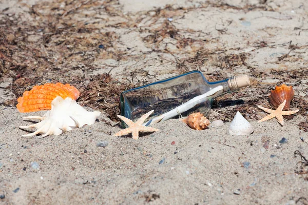 Μήνυμα σε ένα μπουκάλι στην παραλία με κοχύλια και αστερίες — Φωτογραφία Αρχείου