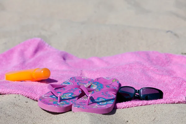 与人字拖、 沙滩巾、 防晒霜和太阳镜在海滩上 — 图库照片