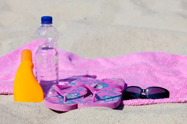 Détente sur la plage avec crème solaire et bouteille d'eau — Photo