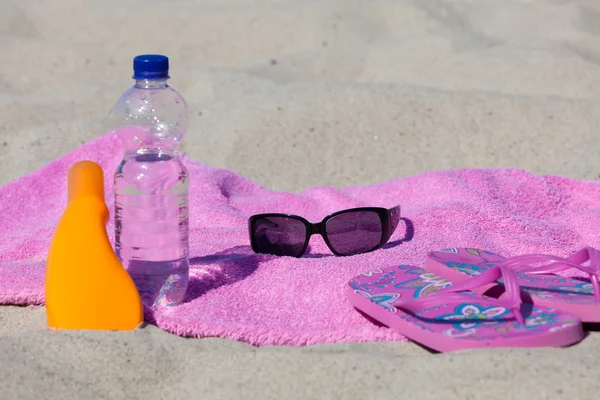 Relajarse en la playa con crema solar y botella de agua — Foto de Stock