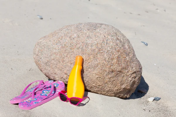 Lunettes de soleil, tongs et crème solaire sur la plage de sable — Photo