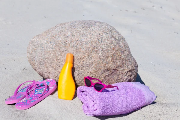 Óculos de sol, chinelos, protetor solar e uma toalha de banho na praia — Fotografia de Stock