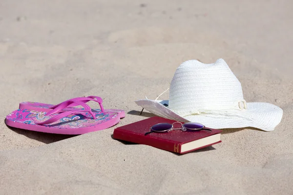 Bir kitap ve bir hasır şapka sahilde ve rahatla — Stok fotoğraf