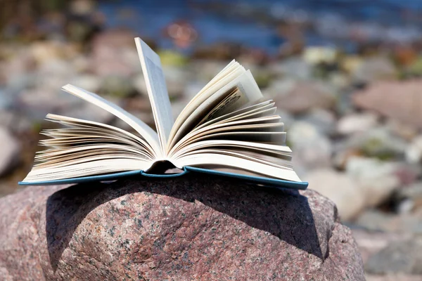 An opened book lies on a rock on the beach — Stock Photo, Image
