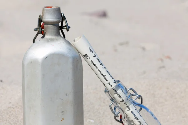 Una mensa e un messaggio in una bottiglia sono nella sabbia del deserto — Foto Stock