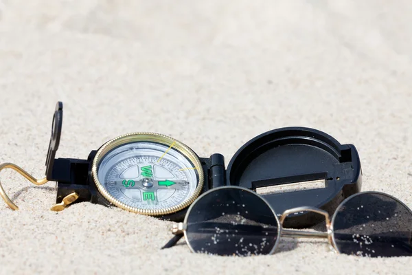 stock image A compass and sunglasses lying on the hot desert sand