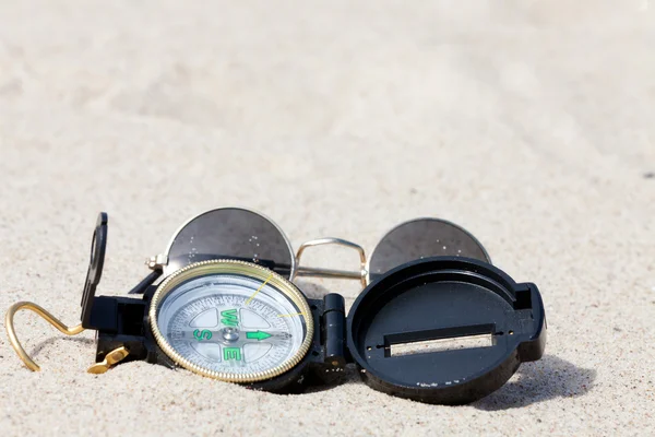 stock image A compass and sunglasses lying on the hot desert sand