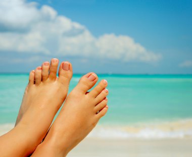 Vacation Concept. Woman's Bare Feet over Sea background clipart