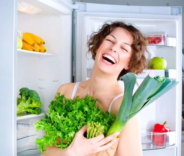 Sağlıklı gıda ile buzdolabı yakınındaki güzel genç kadın — Stok fotoğraf