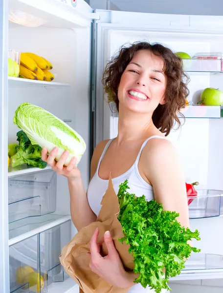 Krásná mladá žena poblíž ledničky se zdravou výživou — Stock fotografie