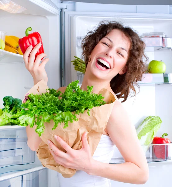 Sağlıklı gıda ile buzdolabı yakınındaki güzel genç kadın — Stok fotoğraf