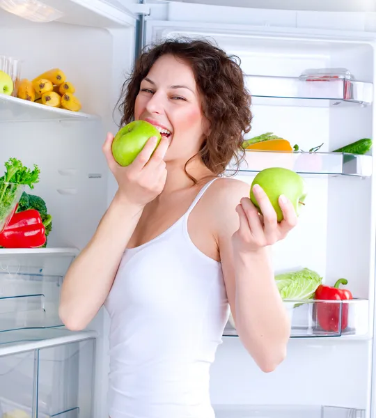 Красивая молодая женщина рядом с холодильником со здоровой пищей — стоковое фото