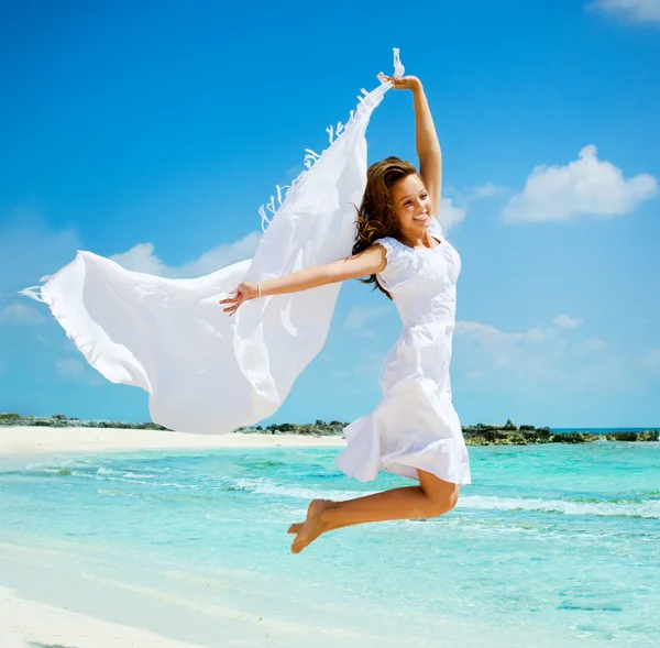 Mooi meisje met witte sjaal springen op het strand — Stockfoto