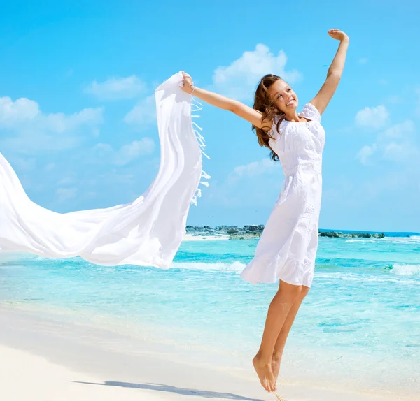 在海滩上跳跃的白色围巾的漂亮女孩 — 图库照片