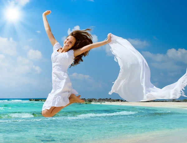 Menina bonita com cachecol branco saltando na praia — Fotografia de Stock