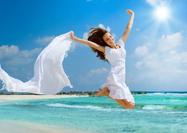 Menina bonita com cachecol branco saltando na praia — Fotografia de Stock
