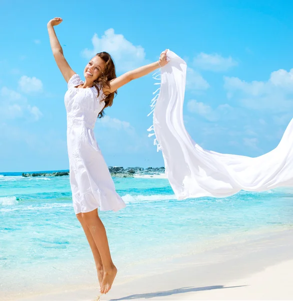 Vacker flicka med vit halsduk hoppa på stranden — Stockfoto