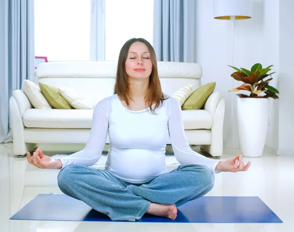 Bella donna incinta che fa yoga a casa — Foto Stock