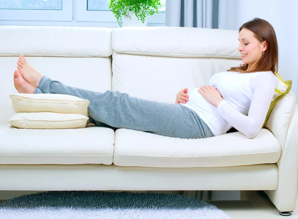 Těhotná žena odpočívá na pohovce doma — Stock fotografie