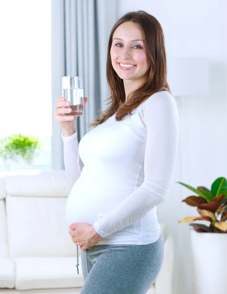 Jovem grávida bebendo água doce em casa — Fotografia de Stock