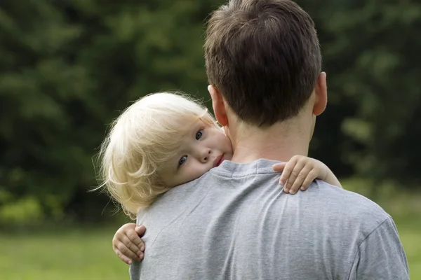 Menino abraçando o pai abraçando em torno dos ombros — Fotografia de Stock